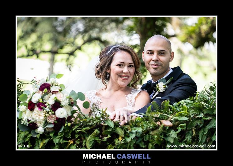 Newly married couple by fern-covered oak tree branch