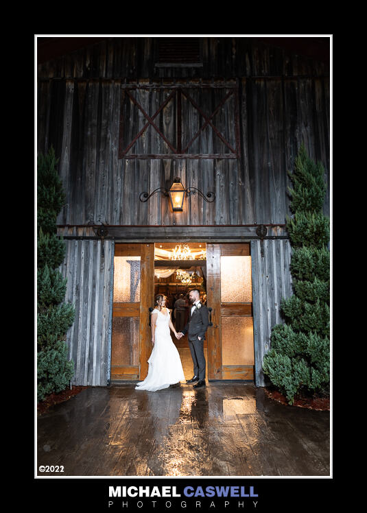 Bride and groom standing in doorway of barn